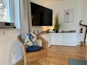 Ferienwohnung Küstenkind im Haus Strandbummler Baabe في بابي: كرسي الخوص في غرفة المعيشة مع التلفزيون