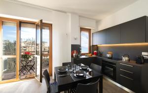 a kitchen with black cabinets and a table with chairs at LA TERRAZZA VISTA DUOMO, piscina e campi da tennis in Milan
