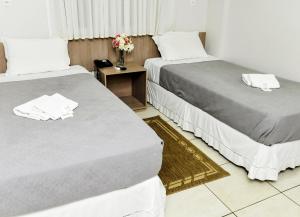 two beds in a room with a vase of flowers at Vivendas Hotel in Erechim +70 photos