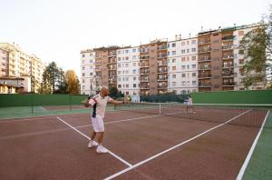 two men playing tennis on a tennis court at LA TERRAZZA VISTA DUOMO, piscina e campi da tennis in Milan
