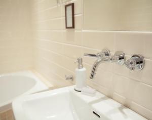 a white bathroom with a sink and a faucet at Villa Sjötorp in Ljungskile