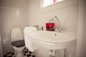 La salle de bains blanche est pourvue d'un lavabo et de toilettes. dans l'établissement Villa Sjötorp, à Ljungskile