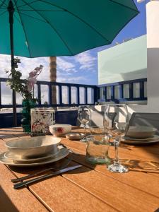 a wooden table with plates and glasses and an umbrella at TK OCEANVIEW Apartment in Puerto del Carmen