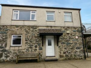a stone house with a white door and a bench at Dinas in Pwllheli