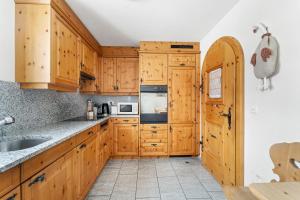 Una cocina con gabinetes de madera y un fregadero. en Chalet St Moritz, en Madulain