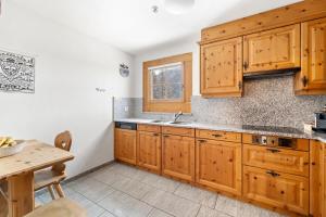 Una cocina con armarios de madera y una mesa. en Chalet St Moritz, en Madulain