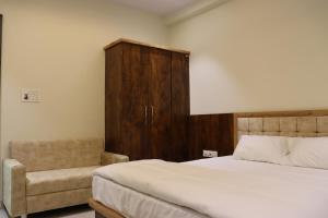 a bedroom with a bed and a chair at Hotel Panna Shree in Ujjain