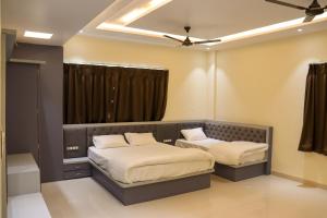 a bedroom with two beds and a window with curtains at Hotel Panna Shree in Ujjain +16 photos