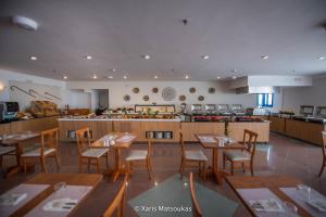 a restaurant with tables and chairs and a kitchen at Ilios Suites in Kato Gouves