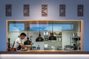 a man is preparing food in a kitchen at Ilios Suites in Kato Gouves