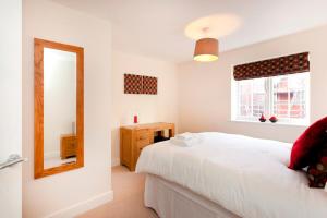 a bedroom with a white bed and a mirror at DBS Serviced Apartments - The Coach House in Castle Donington