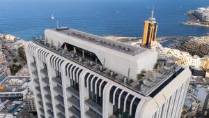 a large white building next to the ocean at Oasis on the 27th, Mercury Tower in St Julian's