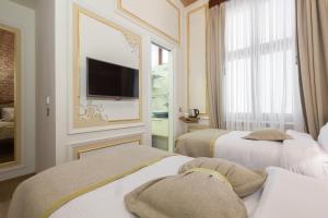 twee bedden in een kamer met een tv aan de muur bij Hotel Pera Parma in Istanbul