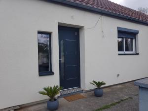 una porta blu su una casa bianca con due piante di Maison entre CHU et Cézeaux- Parking gratuit a Beaumont