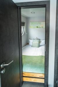 a small bedroom with a bed and a glass door at Rode Houseboat Zwartsluis in Zwartsluis