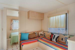 a small room with a couch with colorful pillows at Mobile Home Manoli in Chiclana de la Frontera