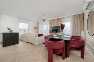 a living room with a table and red chairs at Ekskluzywne Apartamenty Browary Wrocławskie z Klimatyzacją by Renters Prestige in Wrocław +84 photos
