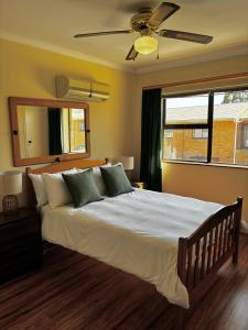 Un dormitorio con una cama grande con ventilador de techo. en Gordon's Bay Townhouse, en Gordonʼs Bay
