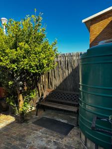 a wooden bench next to a fence and a wooden barrel at Gordon's Bay Townhouse in Gordonʼs Bay