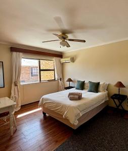 Un dormitorio con una cama con ventilador de techo. en Gordon's Bay Townhouse, en Gordonʼs Bay