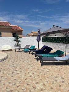a row of lounge chairs and umbrellas on a patio at Villa Veranos, Rojales, Benijofar, Alicante, Valencia in Rojales
