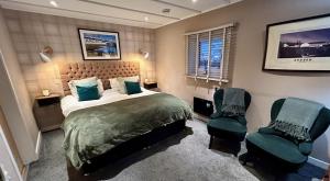 a bedroom with a bed and two chairs at Lochindaal Hotel in Port Charlotte