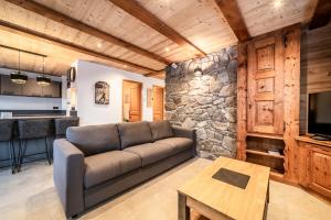 Una sala de estar con un sofá y una pared de piedra. en LES SERMES M304, en Morzine