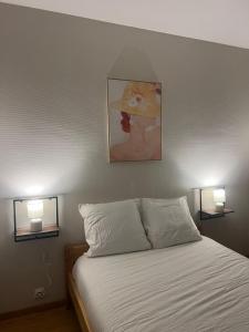 a bedroom with a bed with two lights on the wall at Charmant F2 au cœur de Royat in Royat