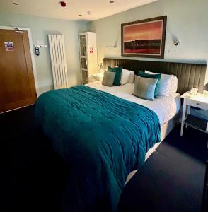 a hotel room with a large bed with green blanket at Lochindaal Hotel in Port Charlotte
