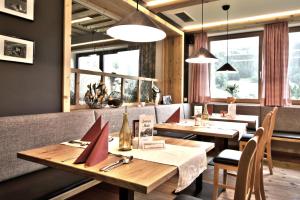 restauracja z drewnianymi stołami, krzesłami i oknami w obiekcie Berghotel Lämmerhof w mieście Sankt Martin am Tennengebirge