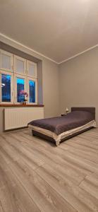 a bedroom with a large bed in a room with wooden floors at Apartament Starówka in Konin