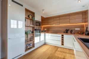a kitchen with white cabinets and wooden walls at Vignes & Tropiques - Terrasse - Wifi - Clim - Parking in Bennwihr +40 photos