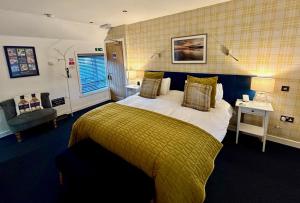 a bedroom with a large bed with a yellow blanket at Lochindaal Hotel in Port Charlotte