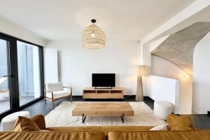a living room with a couch and a table at Villa d’architecte contemporaine - Vue mer 180 in Larmor-Plage