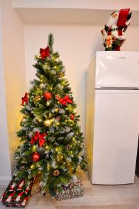 ein Weihnachtsbaum neben einem weißen Kühlschrank in der Unterkunft Royal Accommodation in Bukarest