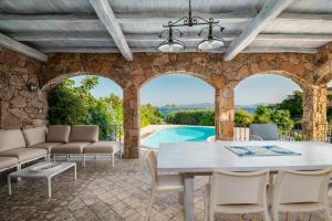 a patio with a table and chairs and a pool at Villa Mimosa in Golfo Aranci