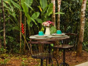 a table with two cups and a vase with flowers on it at Chalés Pura Vida in Itacaré