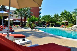 een zwembad met stoelen en parasols naast een hotel bij Servotel Saint-Vincent in Nice