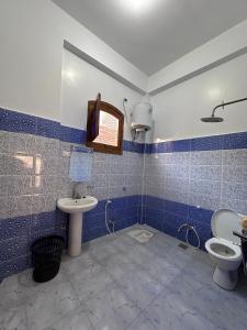 La salle de bains est pourvue de carrelage bleu, d'un lavabo et de toilettes. dans l'établissement Ashry, à Al Aqālitah