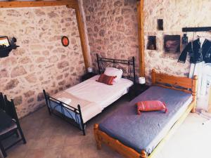 two beds in a room with a stone wall at Το Λαϊνάκι by Fox Tale Guest House in Fternón