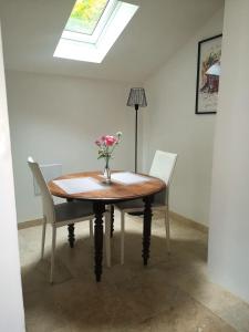 a table with chairs and a vase of flowers on it at Meulière de Charme in Maincy