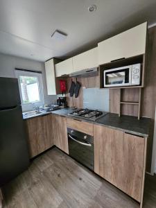 a kitchen with a stove and a microwave at Jolie Mobil home 103 in Saint-Jean-de-Monts
