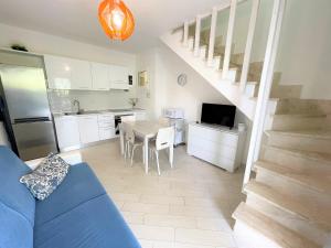 cocina y sala de estar con sofá azul y mesa en Affittimoderni Viddalba Bouganville VIBO09, en Viddalba
