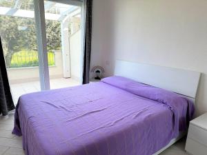 1 cama con manta morada en un dormitorio en Affittimoderni Viddalba Bouganville VIBO09, en Viddalba