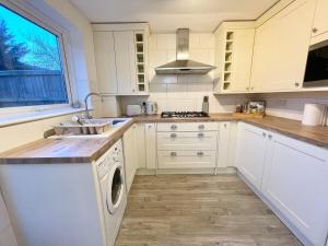 a white kitchen with a sink and a dishwasher at Large home near shops and resturants in lovely area wt parking in Kent