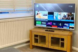 a flat screen tv sitting on top of a wooden stand at Large home near shops and resturants in lovely area wt parking in Kent