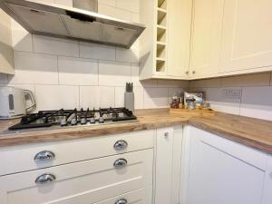 a kitchen with white cabinets and a stove top oven at Large home near shops and resturants in lovely area wt parking in Kent +14 photos