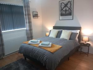 a bedroom with a bed with two towels on it at Douglas Apartment - Trains to Edin & Glasgow - Private Parking in Airdrie +15 photos