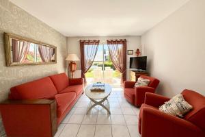 a living room with two red couches and a table at Charmante maison de vacances entre bourg et plages in Ploemeur
