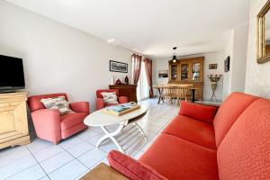 a living room with a red couch and a table at Charmante maison de vacances entre bourg et plages in Ploemeur